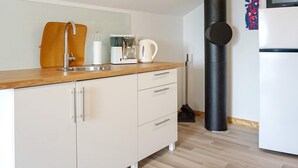 A modern kitchen with a sink, coffee maker, kettle, and a black cylindrical object, possibly a vacuum cleaner. - 4 Person Holiday Home in Kungshamn (Kungshamn)
