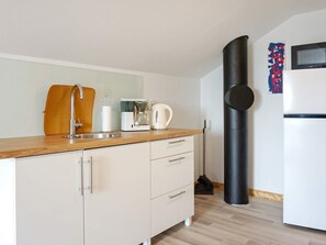 Une cuisine moderne équipée d’un évier, d’une machine à café, d’une bouilloire et d’un objet cylindrique noir, qui pourrait être un aspirateur.