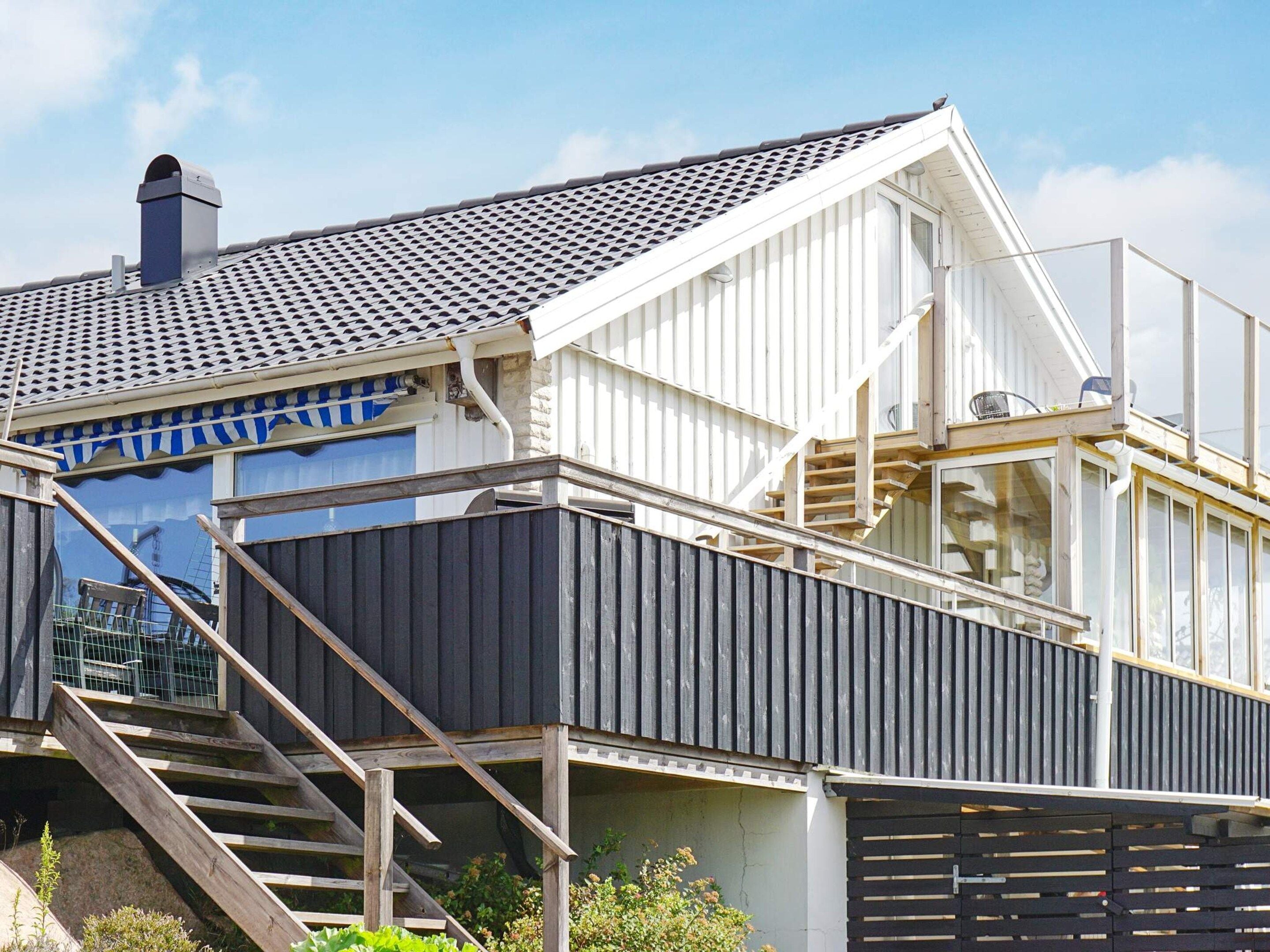 Een modern huis met een schuin dak, een zichtbare schoorsteen en een trap die naar een terras leidt.
