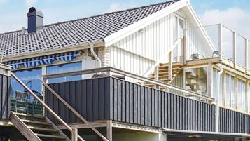Een modern huis met een schuin dak, een zichtbare schoorsteen en een trap die naar een terras leidt.
