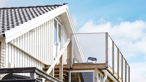 A building with a sloped roof, a balcony with a chair, and a window. - 4 Person Holiday Home in Kungshamn (Kungshamn)
