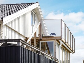 Un bâtiment doté d’un toit en pente, d’un balcon avec une chaise et d’une fenêtre.