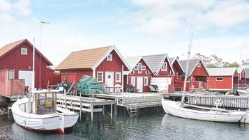 A harbor with red wooden buildings, a white boat docked at the pier, and another boat moored nearby.