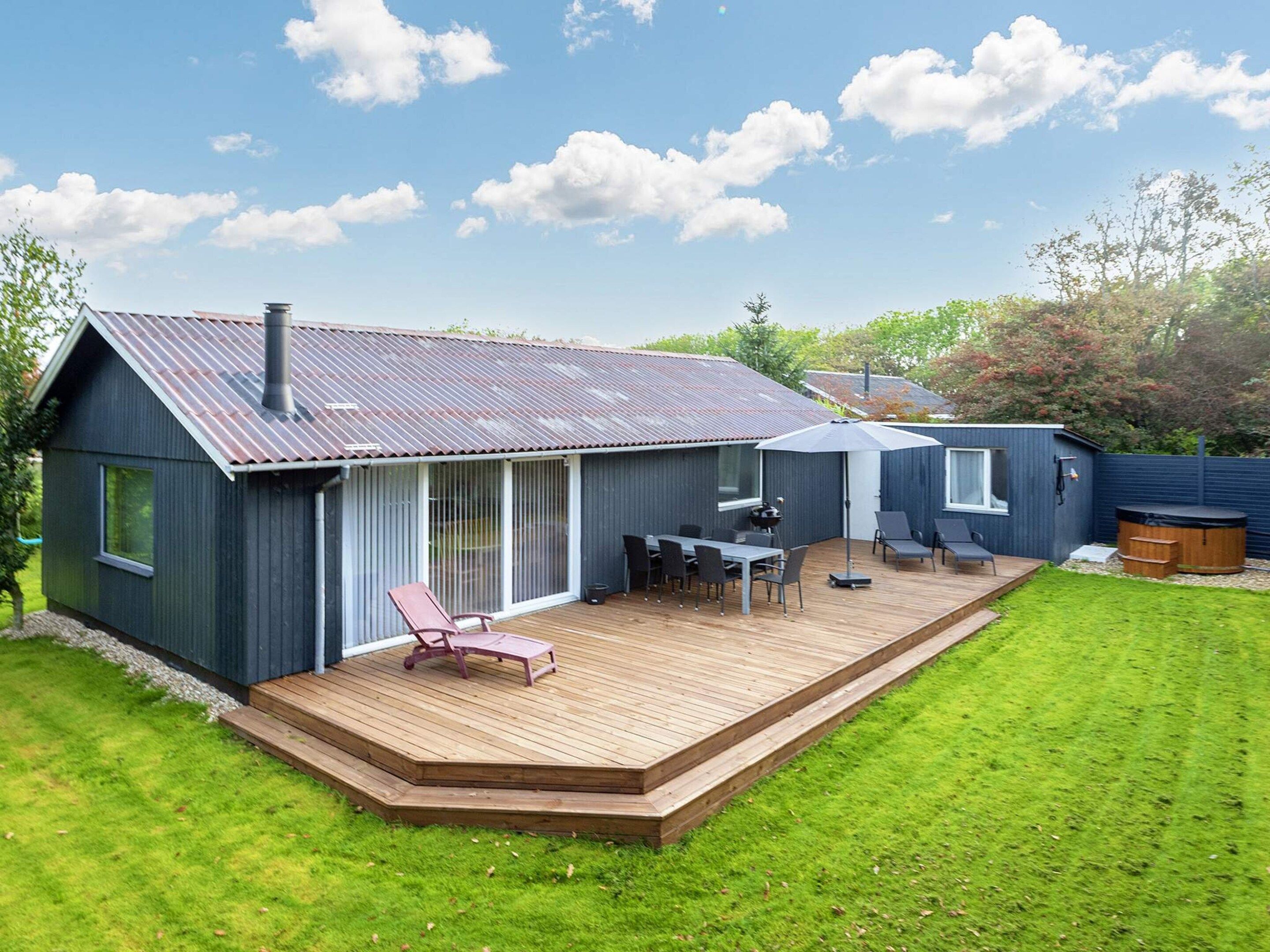 Une maison moderne dotée d’une terrasse, d’un espace barbecue et d’un jacuzzi.
