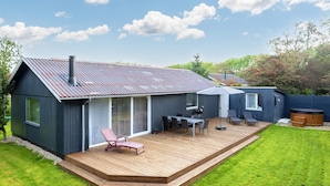 A modern house with a deck, a barbecue area, and a hot tub.