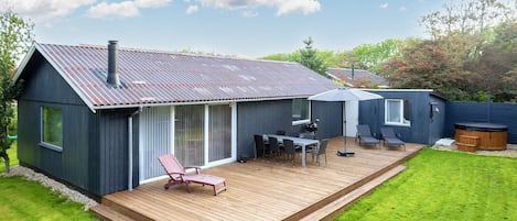 A modern house with a deck, a barbecue area, and a hot tub.