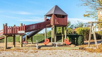 A playground with a slide, climbing structures, and a covered play area.