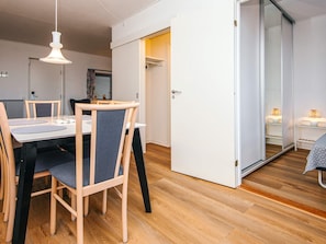 Una zona menjador moderna amb taula i cadires de fusta, llum penjant i una porta corredissa que dona a una altra habitació.