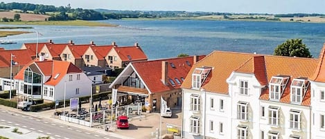 A coastal hotel with red roofs, a parking area, and a view of the sea.