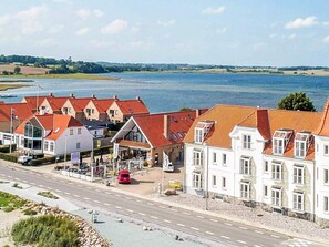 A coastal hotel with red roofs, a parking area, and a view of the sea. - 4 Person Holiday Home in Hejls (Hejls)