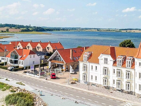 A coastal hotel with red roofs, a parking area, and a view of the sea. - 4 Person Holiday Home in Hejls (Hejls)
