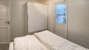 A bedroom with a bed, a wardrobe, and a window with a view of trees and water. - 6 Person Holiday Home in Bremnes (Bomlo)