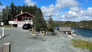 A red cabin with a porch, a gravel driveway, and a lake view. - 6 Person Holiday Home in Bremnes (Bomlo)