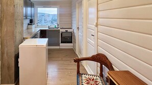 A narrow, single-story building with a kitchen area featuring a sink, stove, and cabinets. A window provides a view of a bridge outside. - 6 Person Holiday Home in Bremnes (Bomlo)