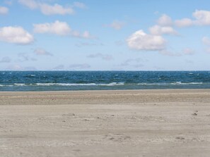 Uma praia com areal e o oceano ao fundo.