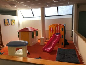 A play area with a slide, a small playhouse, and a bench.