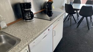 A kitchenette with a coffee maker, a sink, and a dining area with chairs and a table.