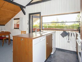 A compact kitchen with a wooden island, white cabinetry, and a large window providing a view of the outdoors.
