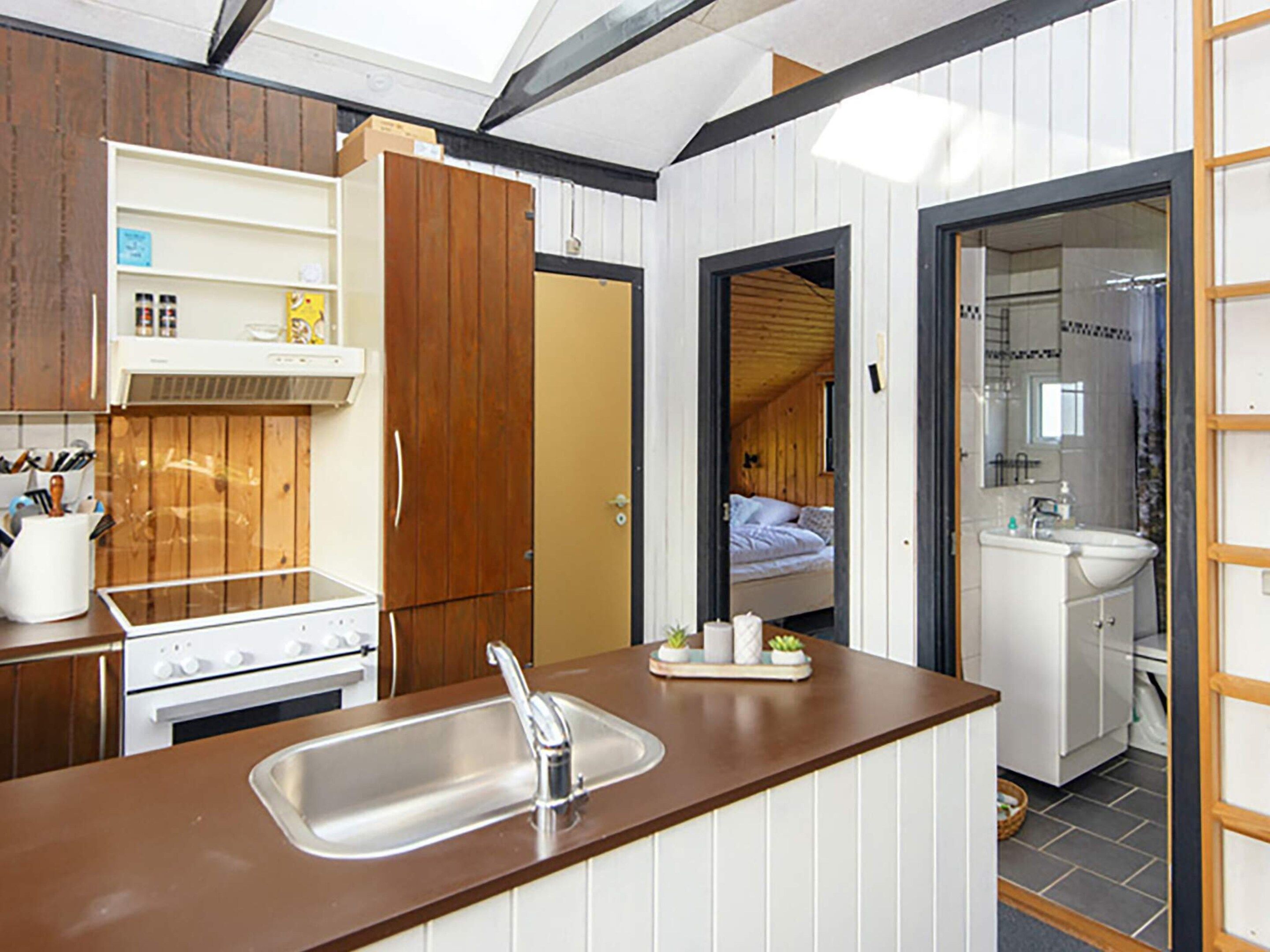 A compact kitchen with a sink, stove, and wooden cabinets.