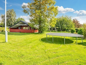 A red house with a lawn, a trampoline, and trees. - 6 Person Holiday Home in Sydals (Sydals)