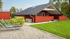 A red building with a sloped roof, a covered porch, and a gravel driveway. - 6 Person Holiday Home in Sydals (Sydals)