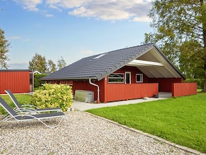 A red building with a sloped roof, a covered porch, and a gravel driveway. - 6 Person Holiday Home in Sydals (Sydals)