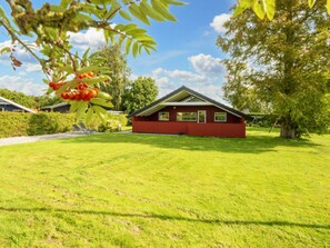 A red building with a sloped roof, surrounded by a well-maintained lawn and trees. - 6 Person Holiday Home in Sydals (Sydals)