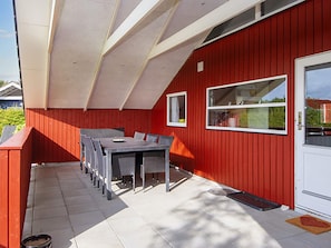 A red building with a covered patio area featuring a table and chairs. - 6 Person Holiday Home in Sydals (Sydals)