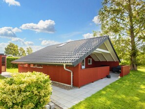 A red building with a sloped roof, a paved driveway, and a well-maintained lawn. - 6 Person Holiday Home in Sydals (Sydals)
