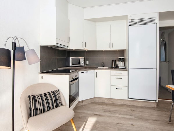 A modern kitchen with white cabinets, a microwave, a coffee maker, and a built-in oven.