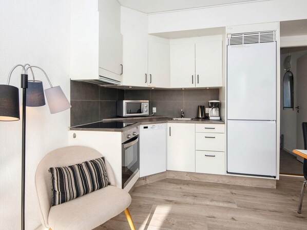 A compact kitchen with white cabinets, a microwave, a coffee maker, and a built-in oven.