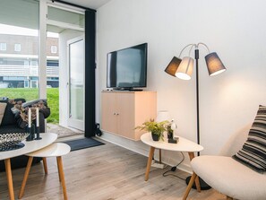 A modern living room with a flat-screen TV, a sofa, a coffee table, and a floor lamp.