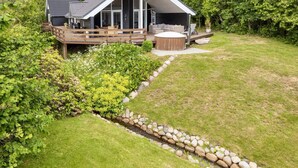 A modern house with a deck, a hot tub, and a stone-lined pathway. - 5 Star Holiday Home in Hadsund (Hadsund)