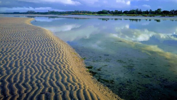 A beach with a sandy shoreline and calm water reflecting the sky. - 5 Star Holiday Home in Hadsund (Hadsund)
