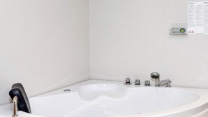 A white bathtub with a handheld showerhead, a faucet, and a control knob. - 5 Star Holiday Home in Hadsund (Hadsund)