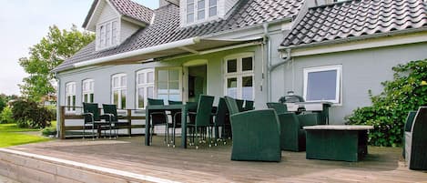 Une maison à deux étages dotée d’un patio couvert aménagé avec du mobilier d’extérieur.