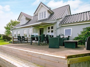 A two-story house with a covered patio area featuring outdoor furniture. - 4 Star Holiday Home in Asperup (Middelfart)