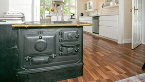 A kitchen with a vintage stove, white cabinets, and a wooden floor. - 4 Star Holiday Home in Asperup (Middelfart)