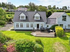 A two-story house with a tiled roof, a front porch, and a well-maintained lawn. - 4 Star Holiday Home in Asperup (Middelfart)