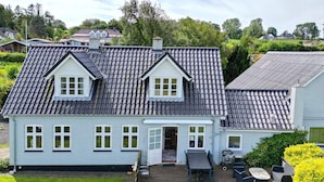 A two-story house with a tiled roof, a front porch with outdoor seating, and a well-maintained lawn. - 4 Star Holiday Home in Asperup (Middelfart)