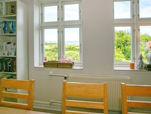 Ein Zimmer mit Meerblick durch ein Fenster, inklusive Heizkörper und einer Bücherwand mit Büchern.