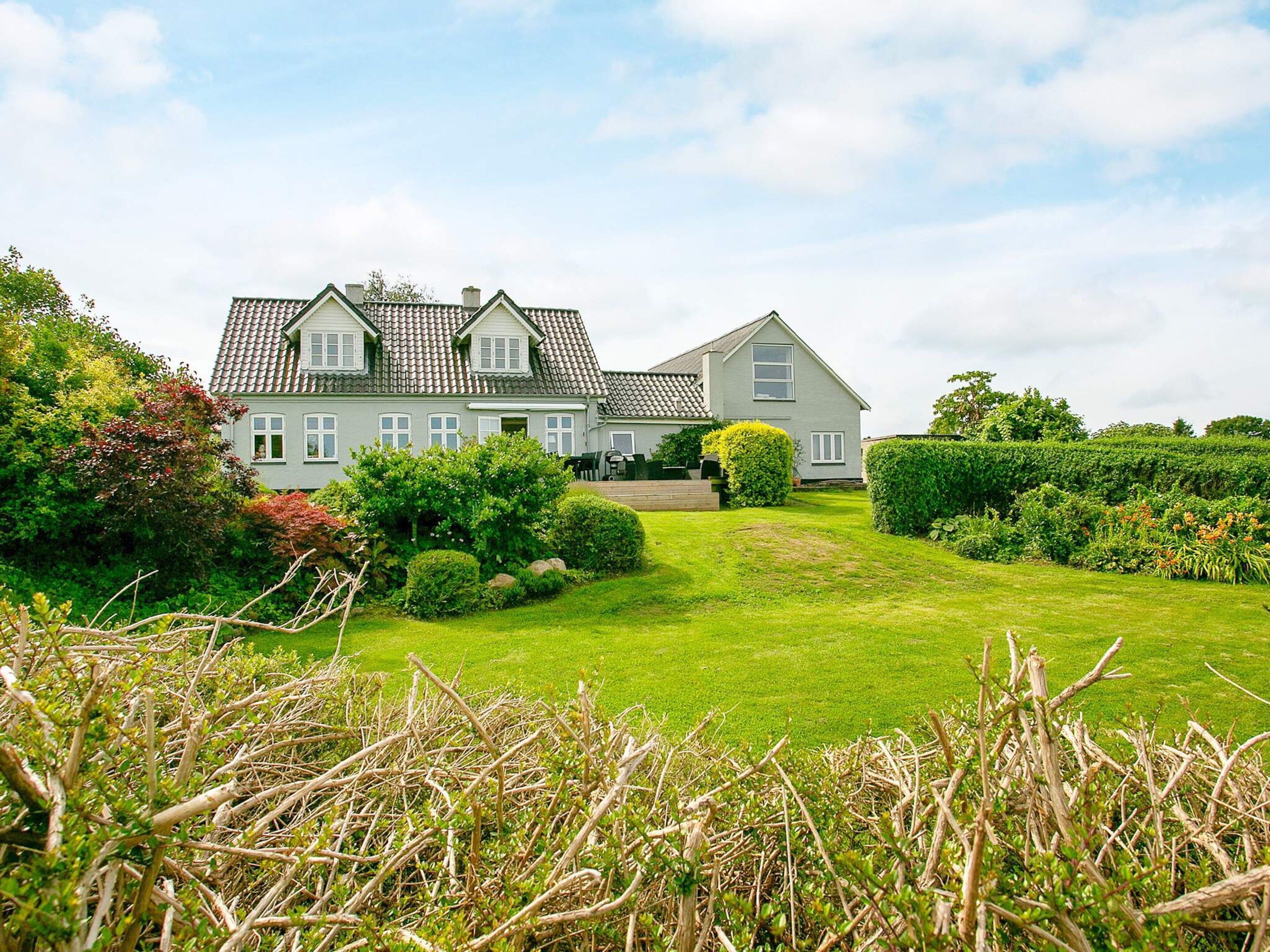 A two-story house with a well-maintained lawn and hedges.