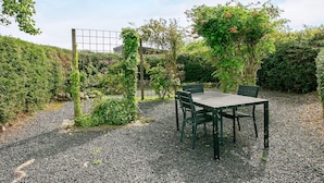 An outdoor seating area with a table and chairs, surrounded by gravel and greenery. - 4 Star Holiday Home in Asperup (Middelfart)