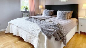 Una camera da letto con un letto grande, una finestra rotonda, una luce a soffitto e un comodino con una lampada.