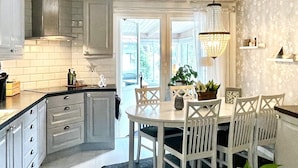 Una cucina moderna con mobili bianchi, un tavolo da pranzo rotondo e un lampadario.