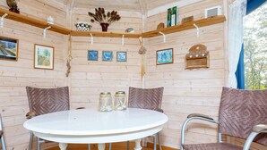 Interior de una cabaña de madera con una mesa redonda, dos sillas y una alfombra tejida.