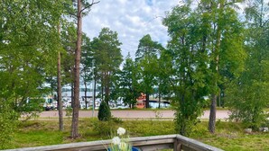 A wooden deck with a round table and chairs, overlooking a marina with boats and a bridge. - 6 Person Holiday Home in Monsteras (Monsteras)