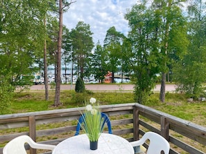 A wooden deck with a round table and chairs, overlooking a marina with boats and a bridge. - 6 Person Holiday Home in Monsteras (Monsteras)