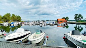 A marina with various boats docked, a wooden dock, and a red building in the background. - 6 Person Holiday Home in Monsteras (Monsteras)