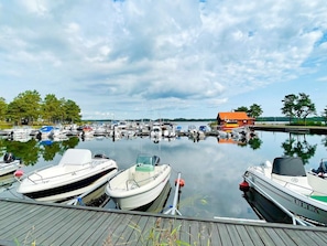 A marina with various boats docked, a wooden dock, and a red building in the background. - 6 Person Holiday Home in Monsteras (Monsteras)